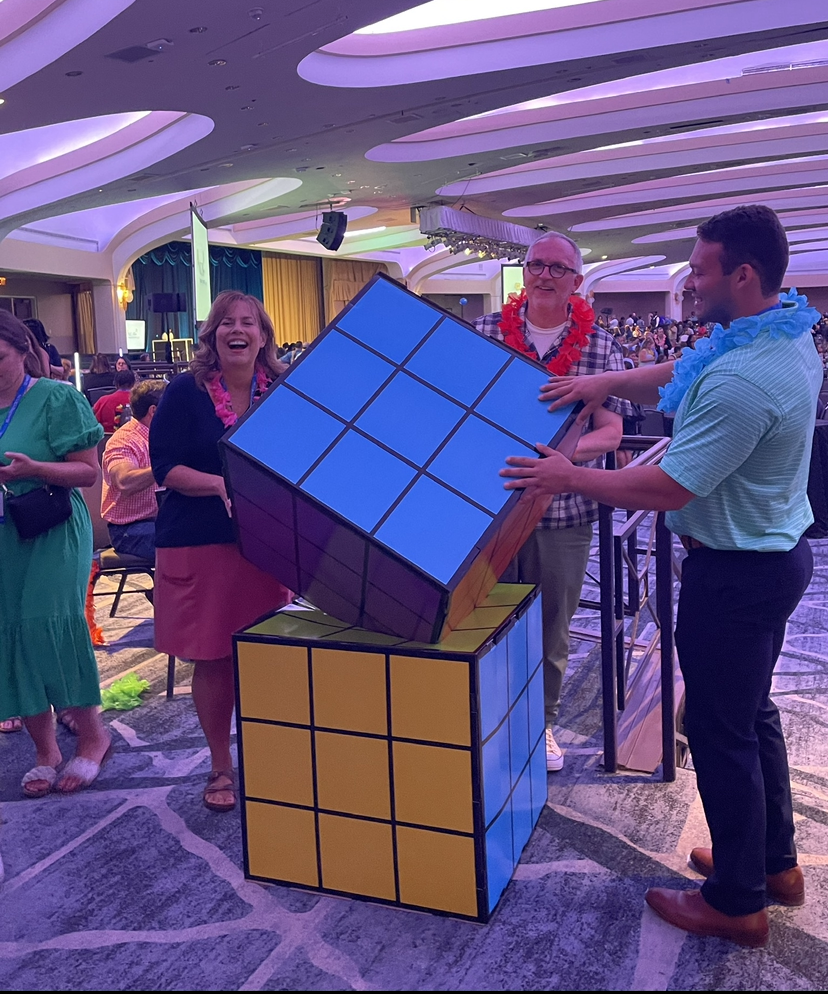 Staff posing with a giant Rubik's Cube 